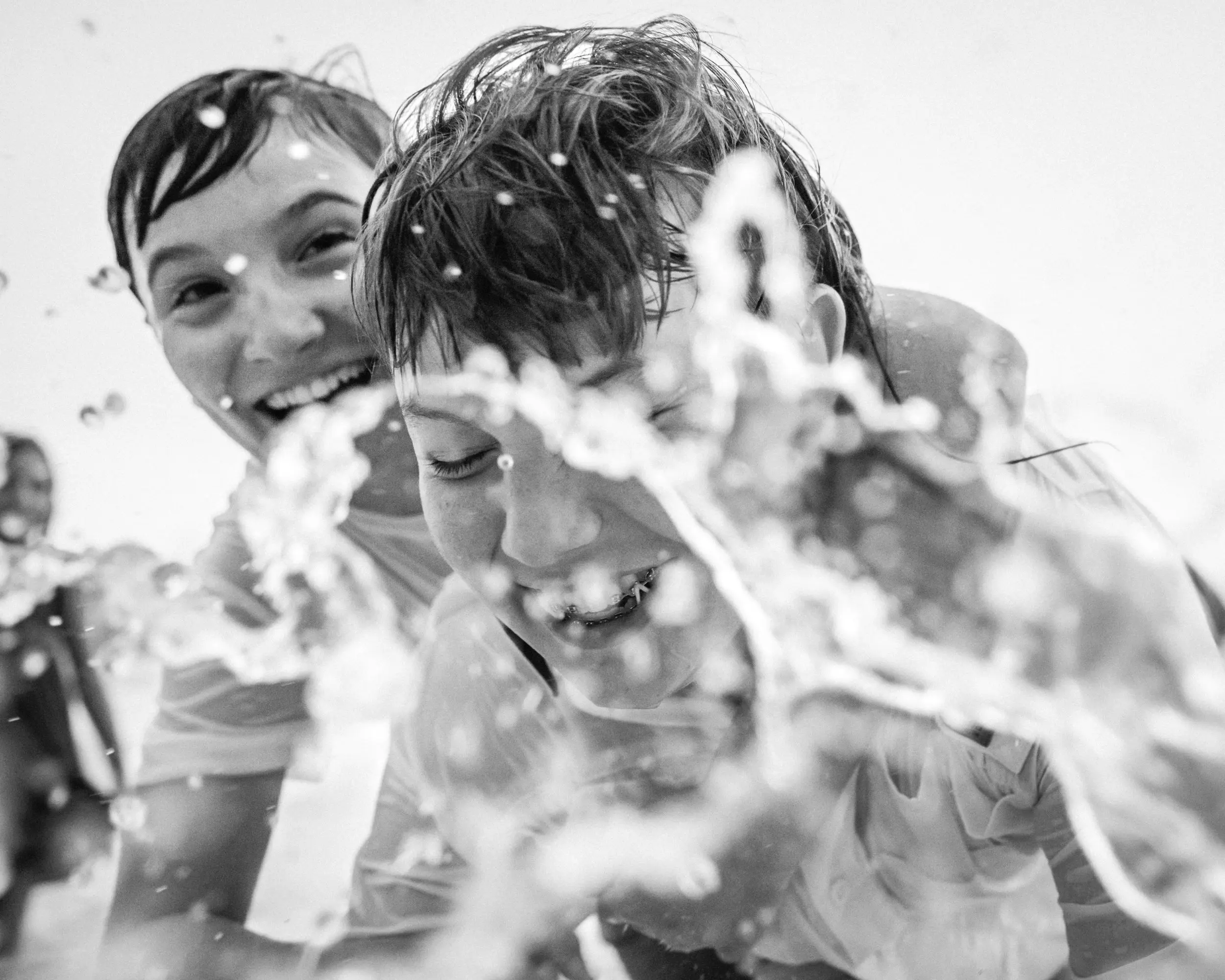 Two girls laughing as water splashes toward the camera.