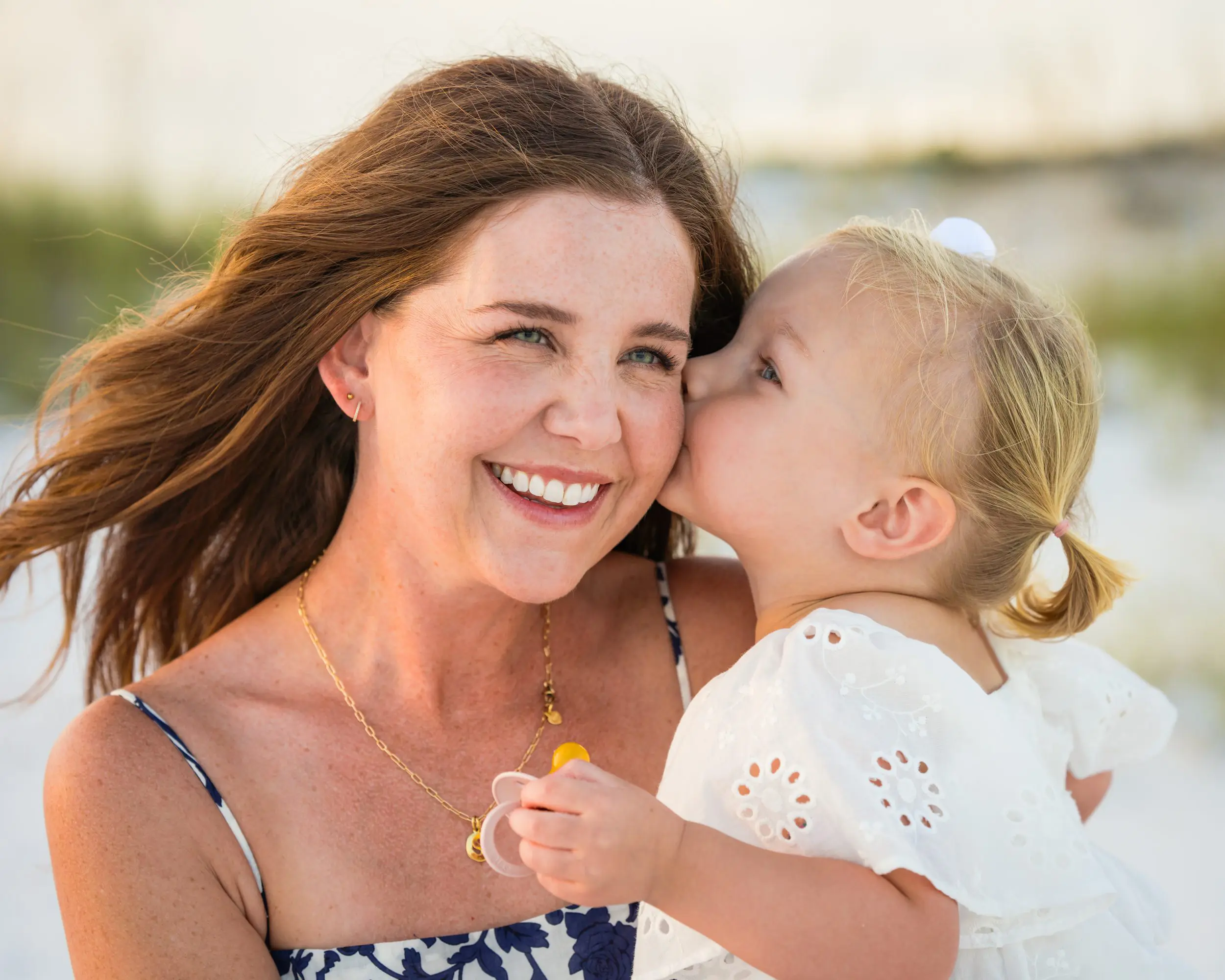 A young child kissing a smiling parent on the cheek.