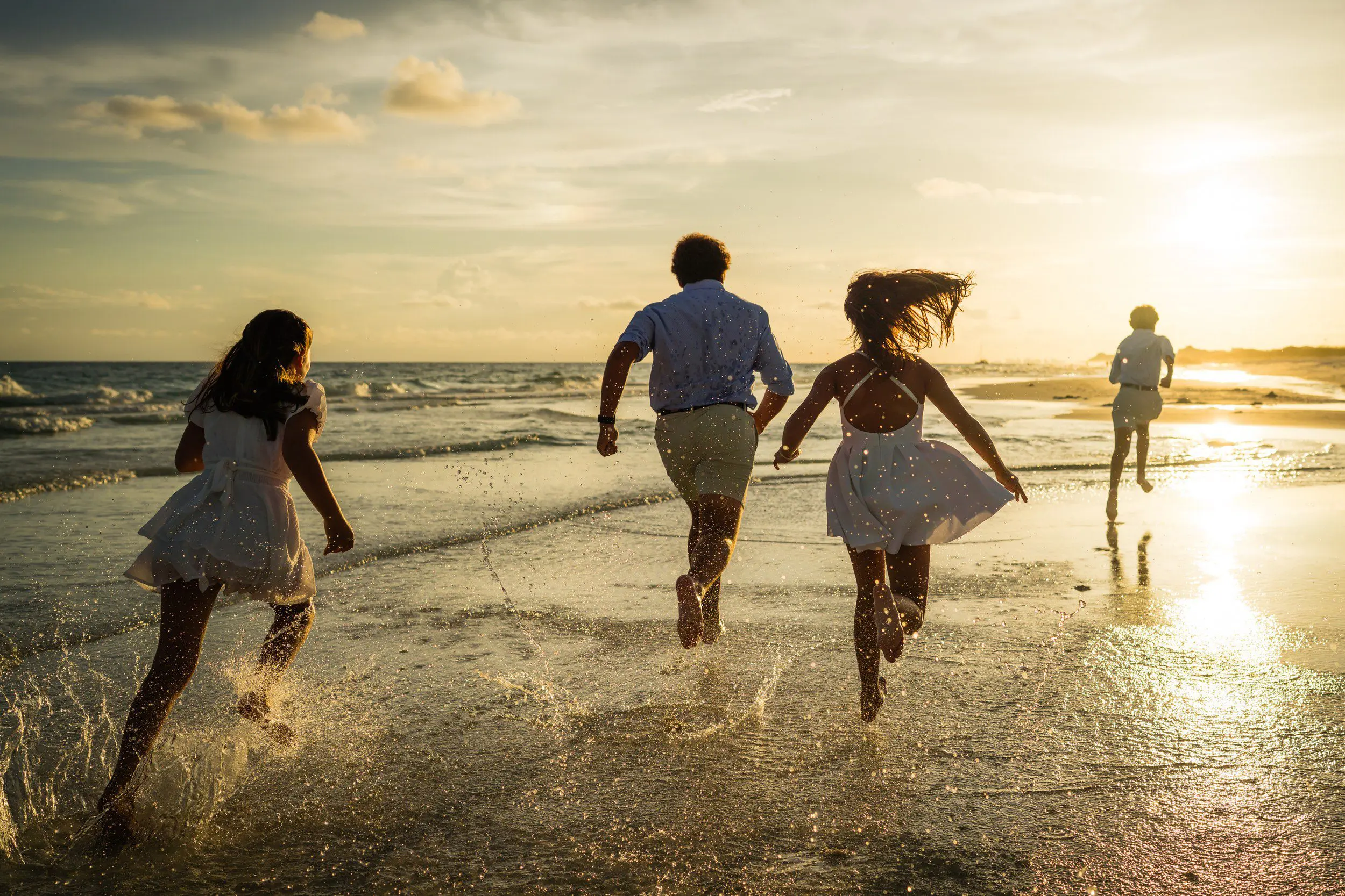 Family running into the surf at sunset during a Destin beach photography session