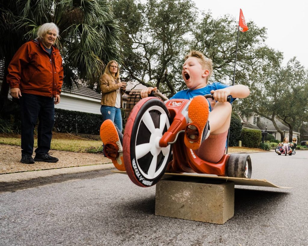 boy jumping big wheel as parents and grandparents watch