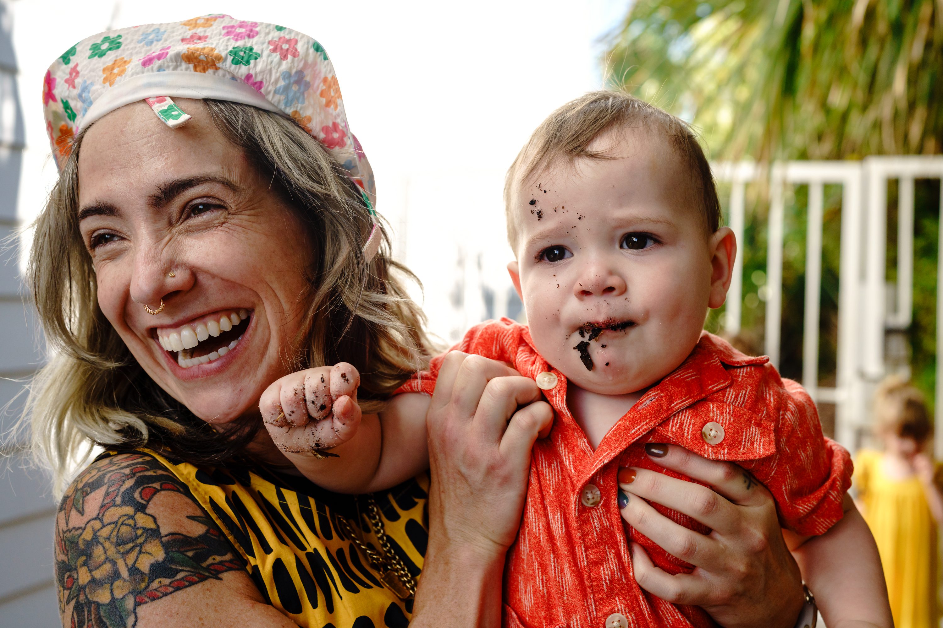 A smiling woman holding a toddler outdoors.