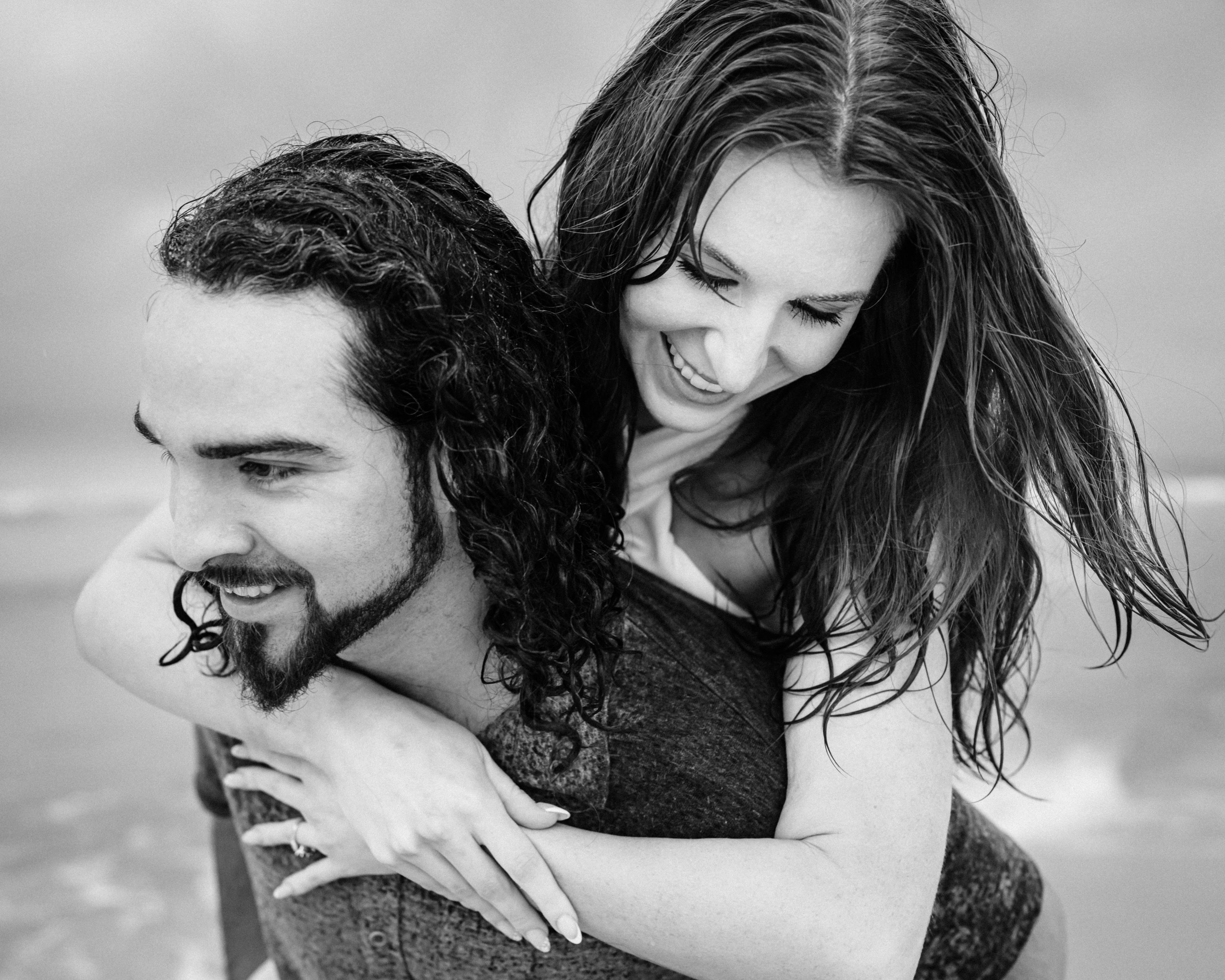 Black-and-white photograph of a woman embracing her partner from behind.