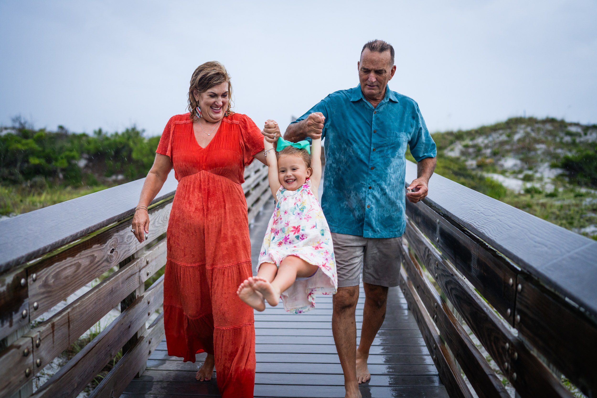 Family walking along a 30A beach boardwalk during a coastal family photography session