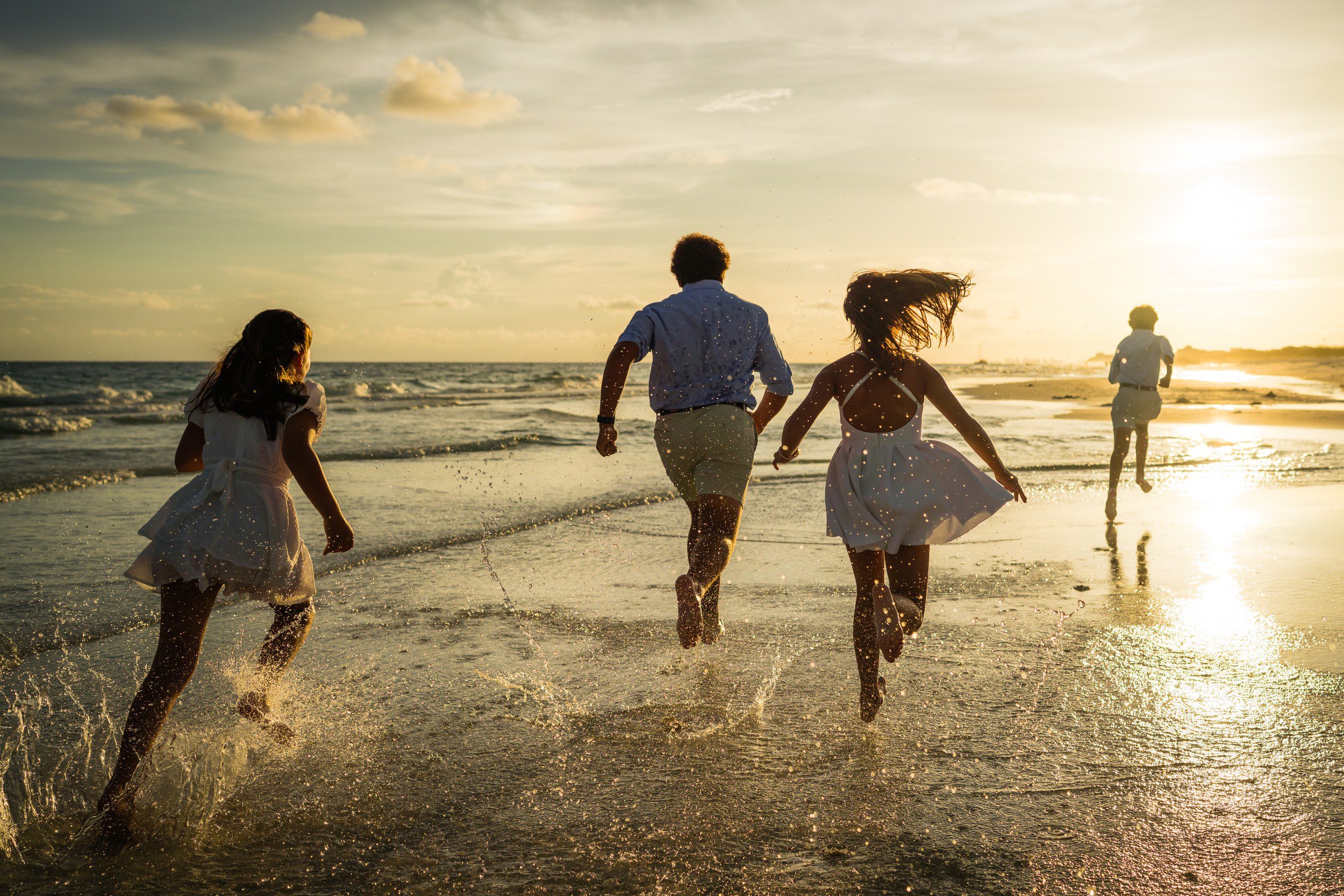 Family running into the surf at sunset during a Destin beach photography session